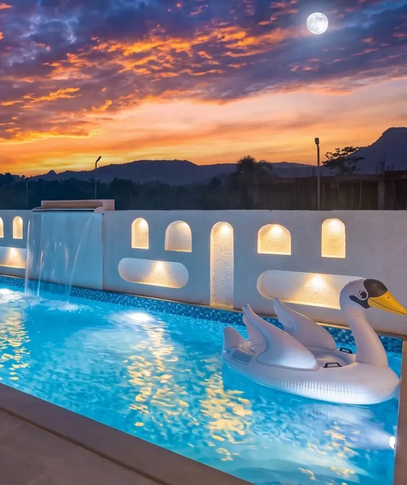 The private pool at sunset, with the sculpted waterfall wall and lit niches